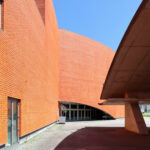 Álvaro Siza Vieira’s Pavilhão Multiusos de Gondomar showcasing a brutalist commercial building with composite materials, extensive brickwork, large daylighting windows, and a functional design emphasizing structural assemblies.