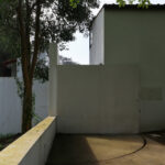 Álvaro Siza Vieira’s Piscina da Quinta da Conceição showcasing a minimalist concrete structure with plastered walls, composite materials, and natural twig shadows creating a shaded, textured façade.