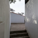 Álvaro Siza Vieira’s Piscina da Quinta da Conceição showcasing a minimalist concrete structure with plastered walls, integrated stairs, and natural daylighting casting shadows on composite material surfaces.