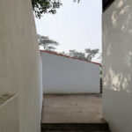 Álvaro Siza Vieira’s Piscina da Quinta da Conceição showcasing a minimalist concrete structure with plastered walls, composite material stairs, and a walkway illuminated by natural daylight creating dynamic shadows.