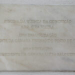 Álvaro Siza Vieira’s Piscina da Quinta da Conceição showcasing a minimalist concrete structure with a silver commemorative plaque and integrated font elements.