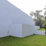Álvaro Siza Vieira’s Piscina da Quinta da Conceição showcasing a minimalist concrete structure with composite material elements, surrounded by landscaped grass and artificial turf under natural daylight and shade.