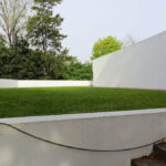 Álvaro Siza Vieira’s Piscina da Quinta da Conceição showcasing a minimalist concrete structure integrated with landscaped grass lawns and shaded garden areas.