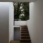 Álvaro Siza Vieira’s Piscina da Quinta da Conceição showcasing a minimalist concrete structure with plaster walls, wooden stairs and handrails, and natural daylighting highlighting the textured building materials.