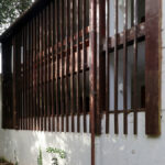 Álvaro Siza Vieira’s Piscina da Quinta da Conceição showcasing a minimalist design with wood-stained hardwood planks, metal and iron fencing, and natural daylighting highlighting the outdoor pool area.