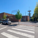 Álvaro Siza Vieira’s Quartel dos Bombeiros Voluntários de Santo Tirso showcasing a modern fire station with clean lines, a flat roof, and integration into the surrounding urban residential area featuring asphalt road surfaces, sidewalks, street lights, and public space elements.