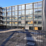 Casa Sacerdotal de São Martinho de Dume by André and António Fontes showcasing a high-rise commercial building with a composite material façade and metal accents in a metropolitan urban setting during daytime.