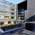 Casa Sacerdotal de São Martinho de Dume by André and António Fontes showcasing a mixed-use high-rise building with a glass façade, composite materials, and modern urban design elements.