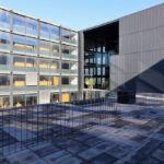 Casa Sacerdotal de São Martinho de Dume by André Fontes and António Fontes showcasing a high-rise apartment building with a composite material façade and extensive glass panels in a metropolitan urban setting during daytime.