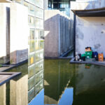 Casa Sacerdotal de São Martinho de Dume by André and António Fontes showcasing a concrete and composite material structure with extensive glass façades, daylighting elements, and a reflecting pool water feature.