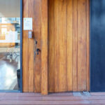 Casa Sacerdotal de São Martinho de Dume by André and António Fontes showcasing a wooden interior with brown stained hardwood plank flooring and a composite material door.