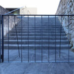 Casa Sacerdotal de São Martinho de Dume by André and António Fontes showcasing a concrete and steel structure with grey composite material stairs, metal handrails, and silver iron elements.