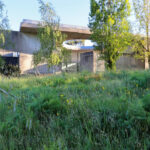 André and António Fontes’ Projecto Homem showcasing a modern structure with a green rooftop surrounded by grass, shrubs, and a diverse plant community on a landscaped land lot.