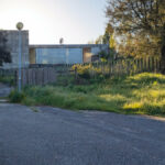 André and António Fontes' Projecto Homem showcasing a concrete and composite material wall structure in a backyard land lot.