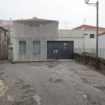 EZZO’s Casa de Leça showcasing a modern concrete façade with composite material walls, a sloped sidewalk, and an adjacent asphalt road surface in a human settlement.