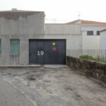 EZZO’s Casa de Leça showcasing a modern residential facade with composite material walls, concrete elements, and a sleek door adjacent to an asphalt road surface in a human settlement.