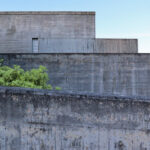 Eduardo Souto de Moura’s Casa 2 no Bom Jesus showcasing a minimalist concrete structure with grey composite walls and large daylighting elements.