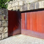 Eduardo Souto de Moura’s Casa em Oliveira do Douro showcasing a minimalist concrete structure with composite material accents, red elements, and dynamic shadow play.