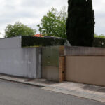 Eduardo Souto de Moura’s Casa na Senhora da Hora showcasing a minimalist concrete and composite material façade with a sloped driveway and adjacent asphalt road surface.