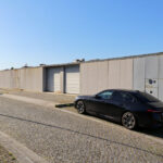 Eduardo Souto de Moura’s Casas Quinta da Avenida showcasing a modern residential design with clean lines, minimalist concrete and glass façades, and an integrated parking area featuring luxury sedans on asphalt.