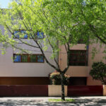 Eduardo Souto de Moura’s Duas Casas na Rua Beato Inácio de Azevedo showcasing two modern residences with minimalist façades, prominent use of natural daylighting, and surrounding tree branches providing shade.