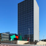 Eduardo Souto de Moura’s Edifício Burgo, a high-rise commercial skyscraper in a metropolitan urban area, featuring a composite material façade under a clear blue daytime sky.