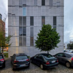 Eduardo Souto de Moura’s Edifício de Habitação Coletiva showcasing a high-rise condominium with a composite material façade, extensive glass panels, and modern urban design elements under daytime lighting.