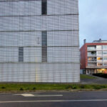 Eduardo Souto de Moura’s Edifício de Habitação Coletiva showcasing a high-rise apartment building with a composite material façade, extensive glass panels, and integrated urban design elements.