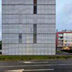 Eduardo Souto de Moura’s Edifício de Habitação Coletiva showcasing a high-rise commercial building with a composite material façade, extensive glass panels, and urban design elements emphasizing daylighting and corporate headquarters functionality.