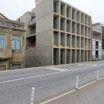 Eduardo Souto de Moura’s Edifício de Habitação e Comércio showcasing a high-rise brutalist concrete apartment and commercial building with a stark, geometric façade.