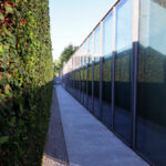 Eduardo Souto de Moura’s Mercado Municipal de Braga reconversion showcasing a modern dance and music school with landscaped hedges, walkways, and a fence along the thoroughfare and road surface.