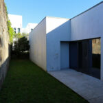 Eduardo Souto de Moura’s Mercado Municipal de Braga reconversion featuring concrete and composite material walls, grey plaster finishes, daylighting effects, and a shaded walkway.