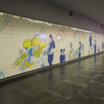 Eduardo Souto de Moura’s Metro do Porto station showcasing concrete and tile flooring, composite material ceiling, painted walls with graffiti and graphic designs, and a modern subway interior.
