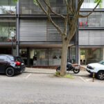 Eduardo Souto de Moura’s Residential Building showcasing a modern apartment complex with multiple balconies, integrated parking spaces featuring various family and luxury vehicles, and a sleek condominium design.