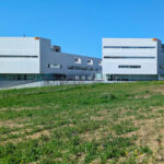 Gonçalo Byrne’s design of Escola de Engenharia II at Universidade do Minho showcasing a modern composite material façade with clean lines, integrated into a campus setting featuring a well-maintained lawn and urban design elements.