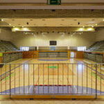 Jorge Nuno Monteiro’s Pavilhão Desportivo Municipal de Santo Tirso showcasing a modern sports venue with a spacious indoor arena, basketball court, net, and polished floor designed for various indoor games and sports.