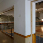 Jorge Nuno Monteiro’s Pavilhão Desportivo Municipal de Santo Tirso showcasing a spacious interior with hardwood plank flooring, plywood ceiling panels, and ample daylighting through large windows.