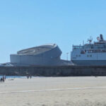 Luís Pedro Silva’s Porto Leixões Cruise Terminal showcasing a modern glass façade with cantilevered roof structures overlooking docked passenger ships and watercraft.