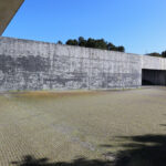 OPERA | Design Matters' Escola de Medicina, Universidade do Minho, showcasing a concrete and composite material façade with grey cement walls and distinct shadow patterns.