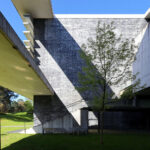 OPERA | Design Matters' Escola de Medicina, Universidade do Minho, showcasing a brutalist concrete structure with composite materials, prominent daylighting features, and shaded geometric forms.