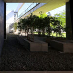 OPERA | Design Matters' Escola de Medicina, Universidade do Minho, showcasing a concrete and metal structure with composite material elements, featuring shaded walkways and dynamic daylighting creating distinct shadows.