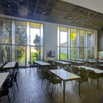 OPERA | Design Matters' Escola de Medicina, Universidade do Minho, showcasing a modern interior with abundant daylighting, sleek chairs, and a restaurant area featuring clean lines and open space.
