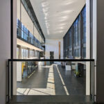 OPERA | Design Matters' Escola de Medicina, Universidade do Minho, showcasing a commercial building interior with a metal and composite material ceiling, extensive glass panels, iron structural elements, and optimized daylighting engineering.