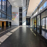 OPERA | Design Matters' Escola de Medicina, Universidade do Minho, showcasing a modern commercial building with a composite material and metal structure, featuring extensive glass façades for daylighting and integrated shading elements in a metropolitan area.