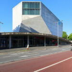 Rem Koolhaas’s Casa da Música showcasing a brutalist concrete and steel commercial building with a distinctive angular form and composite material façade providing shade and structural engineering innovation.