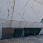Rem Koolhaas’s Casa da Música showcasing a triangular concrete and glass structure with composite materials, featuring brutalist architectural elements and extensive daylighting in a corporate headquarters setting.