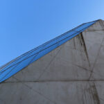 Rem Koolhaas’s Casa da Música featuring a blue composite material exterior with triangular glass panels, symmetrical design, and extensive daylighting on a high-rise headquarters building.