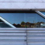 Rem Koolhaas’s Casa da Música showcasing a daytime view of the headquarters with a striking composite material façade, angular glass and metal panels, steel and aluminium structural elements, and prominent triangular shapes with integrated stairs and daylighting features.