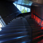 Rem Koolhaas’s Casa da Música showcasing a silver composite material interior with metal handrails, glass elements, modern lighting, and distinctive staircases under a sculpted ceiling.