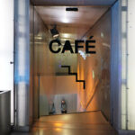 Rem Koolhaas’s Casa da Música interior showcasing modern flooring, dynamic lighting fixtures, sleek furniture, expansive glass walls, and a distinctive ceiling design within a contemporary restaurant setting.